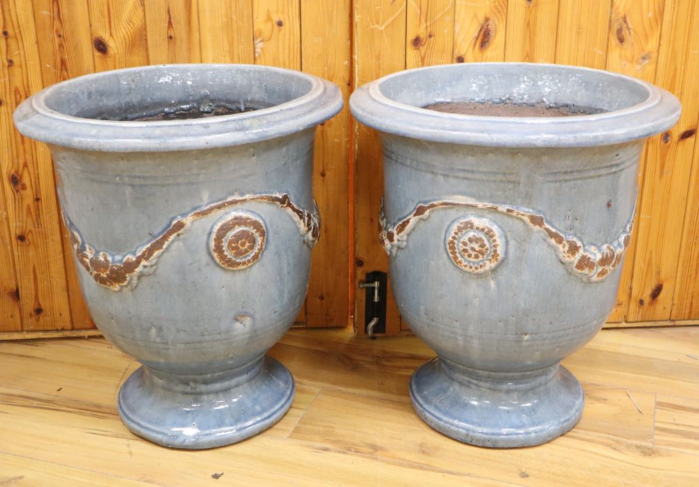 A pair of blue glazed terracotta pots, with swag design, height 51cm